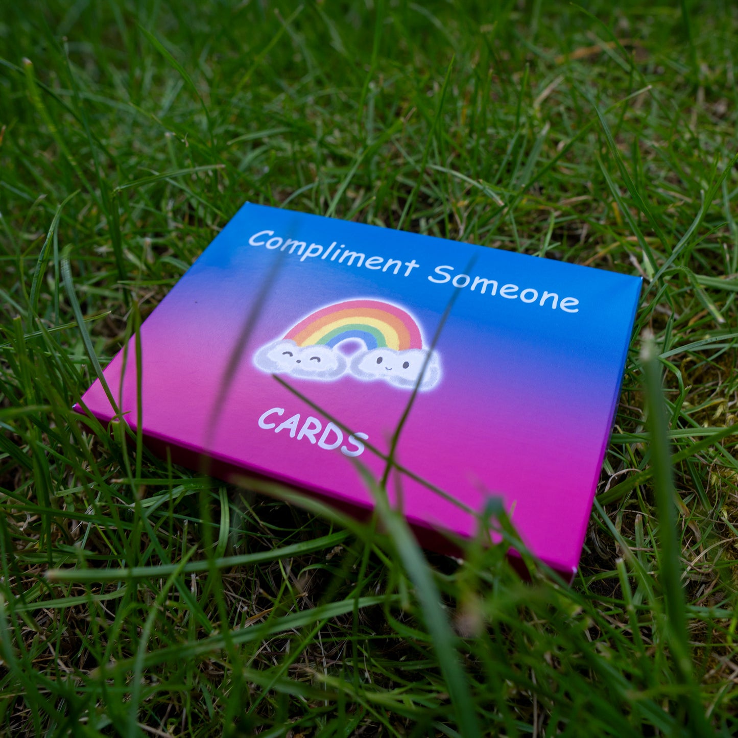 'Compliment Someone' compliment cards box laying on grass